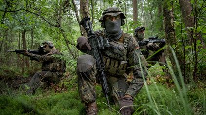 Soldaten der Bundeswehr suchen Deckung in einem Waldstück