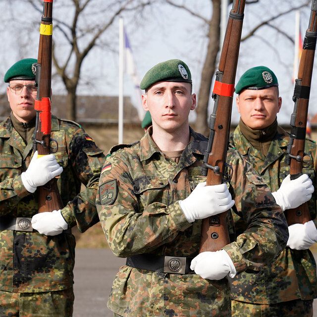 Drei Soldaten in Uniform mit Gewehren