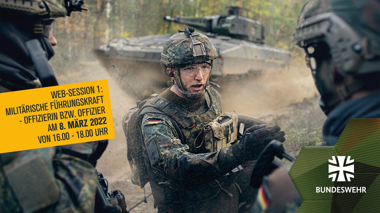 Soldat in Kampfausrüstung spricht mit anderen Soldaten, im Hintergrund ist ein Panzer zu sehen.