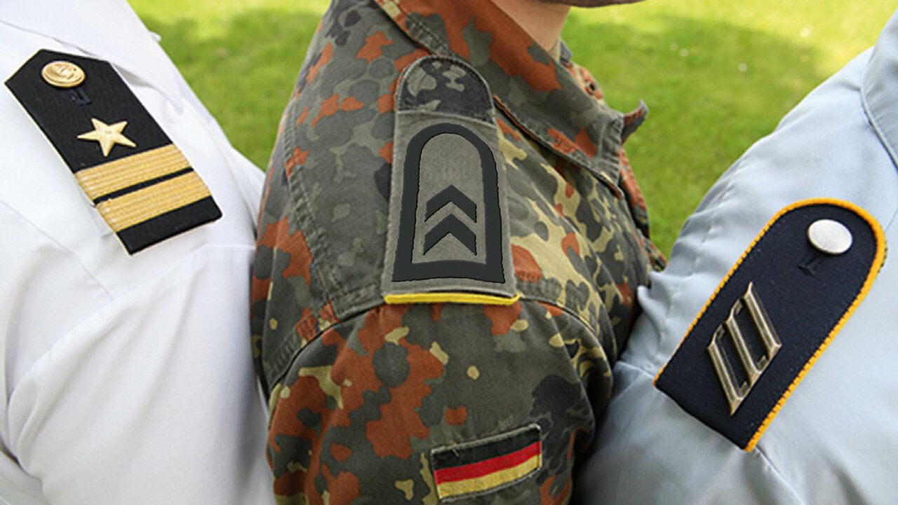 3 Schultern von Soldat_innen sind zu sehen. Die Abzeichen ihrer Dienstgrade sind im Bild zu sehen.