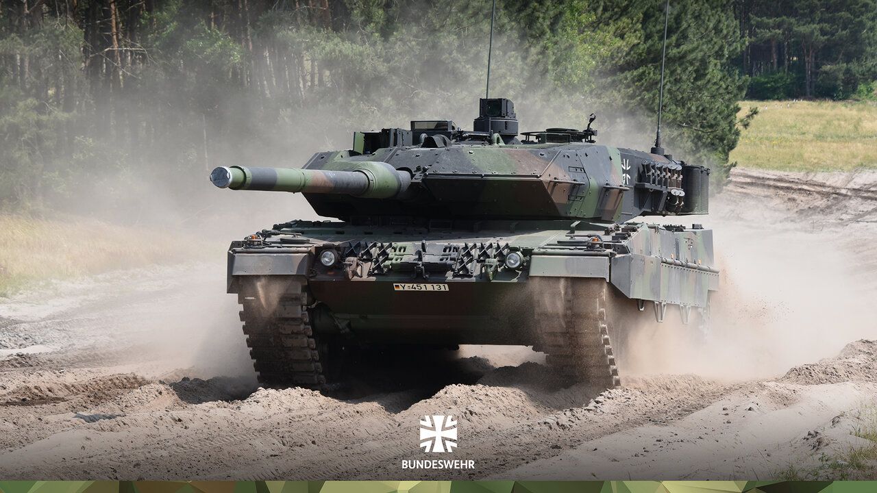 Ein Kampfpanzer Leopard 2A7 in voller Fahrt im staubigen Gelände