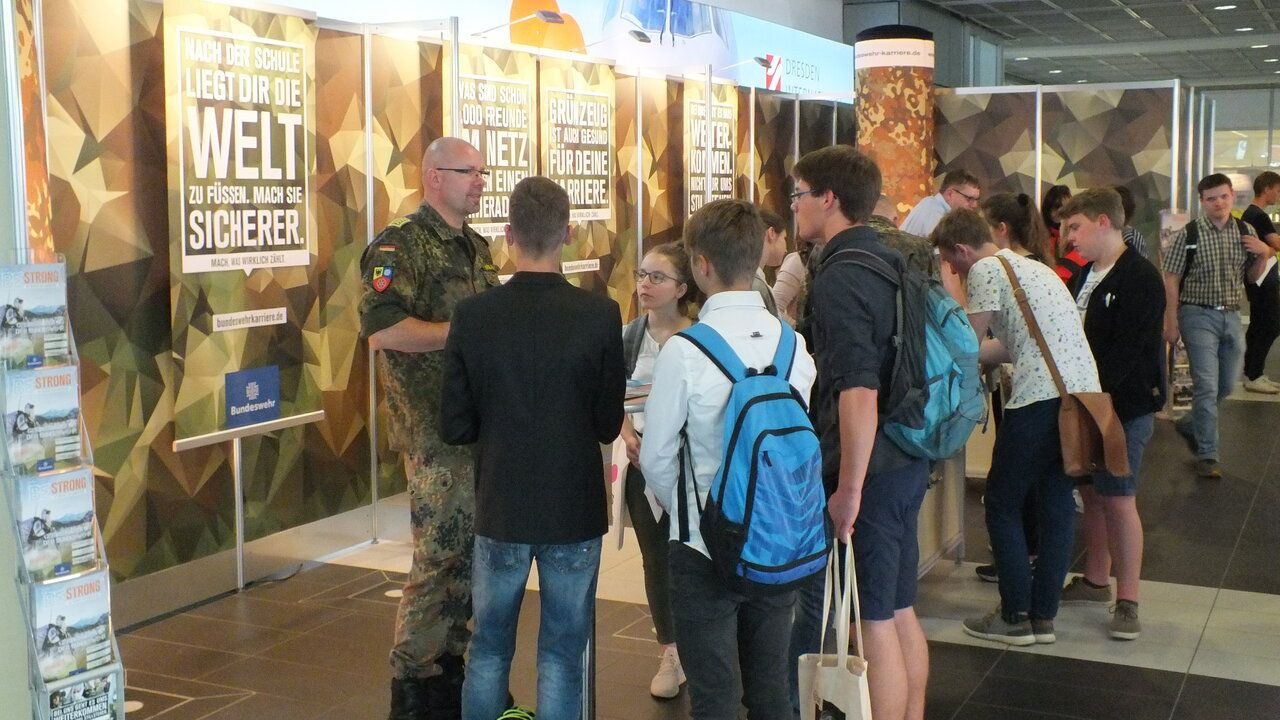 Am Messestand der Bundeswehr berÃ¤t ein Soldat Interessierte Jugendliche und beantwortet Fragen. 