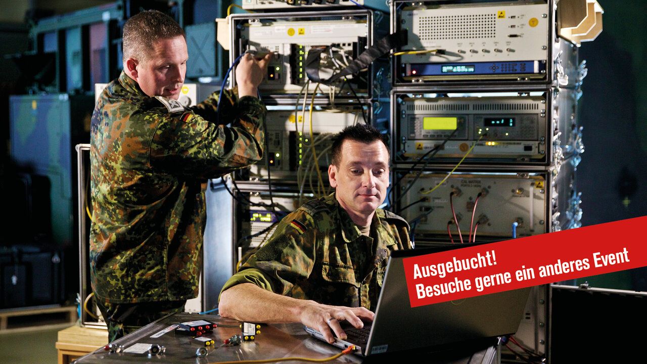 2 Soldaten der Bundewehr im IT-Bataillon arbeiten an einem Laptop der mit einem Server verbunden ist.