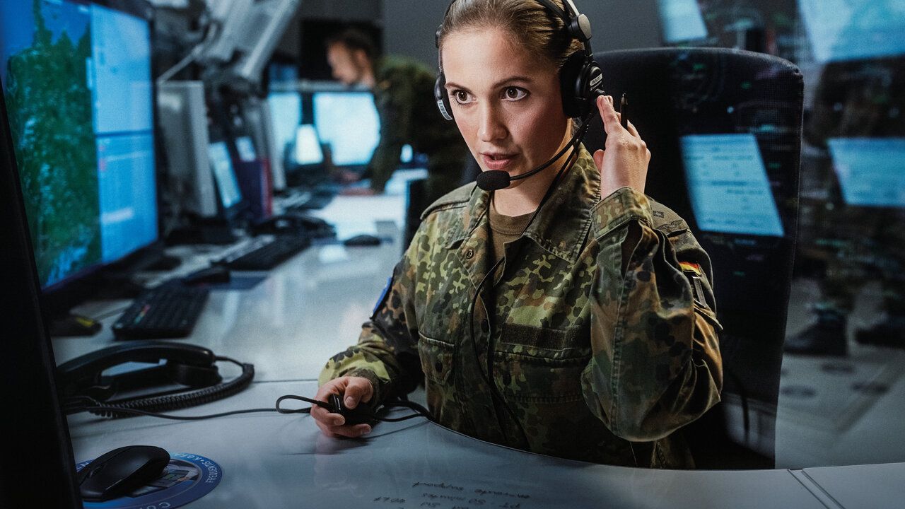 Soldatin mit Headset vor Monitoren