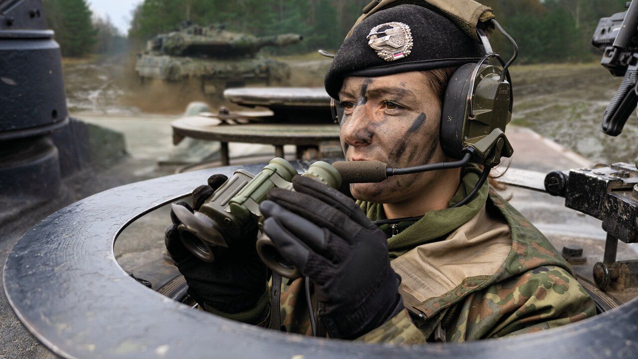 Eine Soldatin mit Fernglas schaut aus einem Panzer heraus