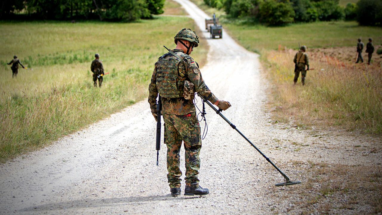 Soldat_innen der Bundeswehr suchen mit Detektoren eine StraÃŸe ab um eine sichere Ãœberquerung zu gewÃ¤hrleisten 