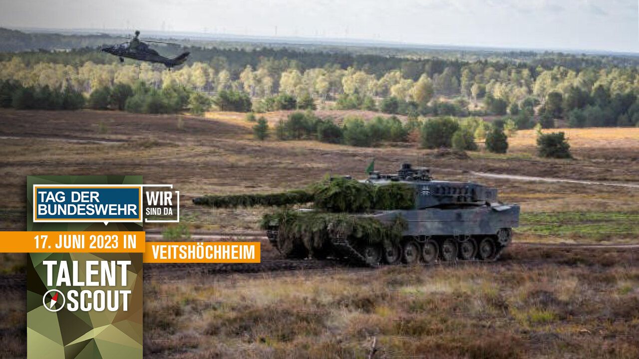 Ein Panzer der Bundeswehr rollt Ã¼ber ein Feld. Im Hintergrund fliegt ein Hubschrauber.