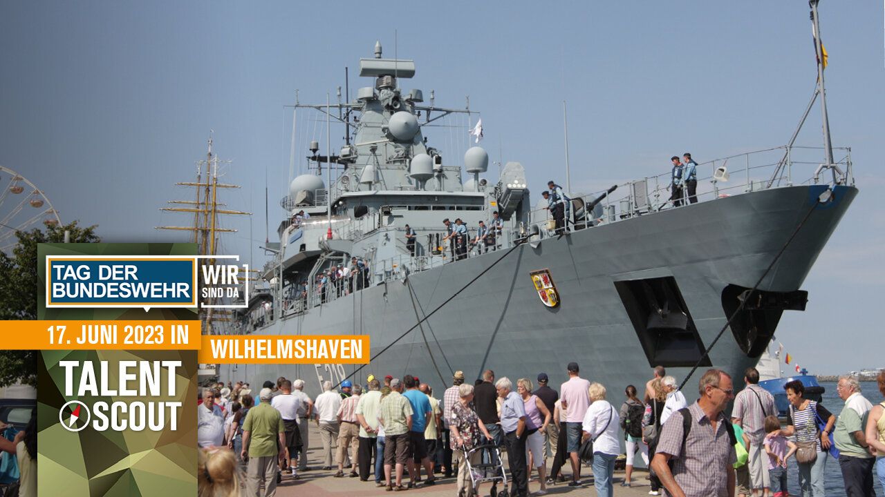 Eine Fregatte der Bundeswehr liegt am Hafen an. Besucherinnen und Besucher laufen entlang und schauen sich die Fregatte an.