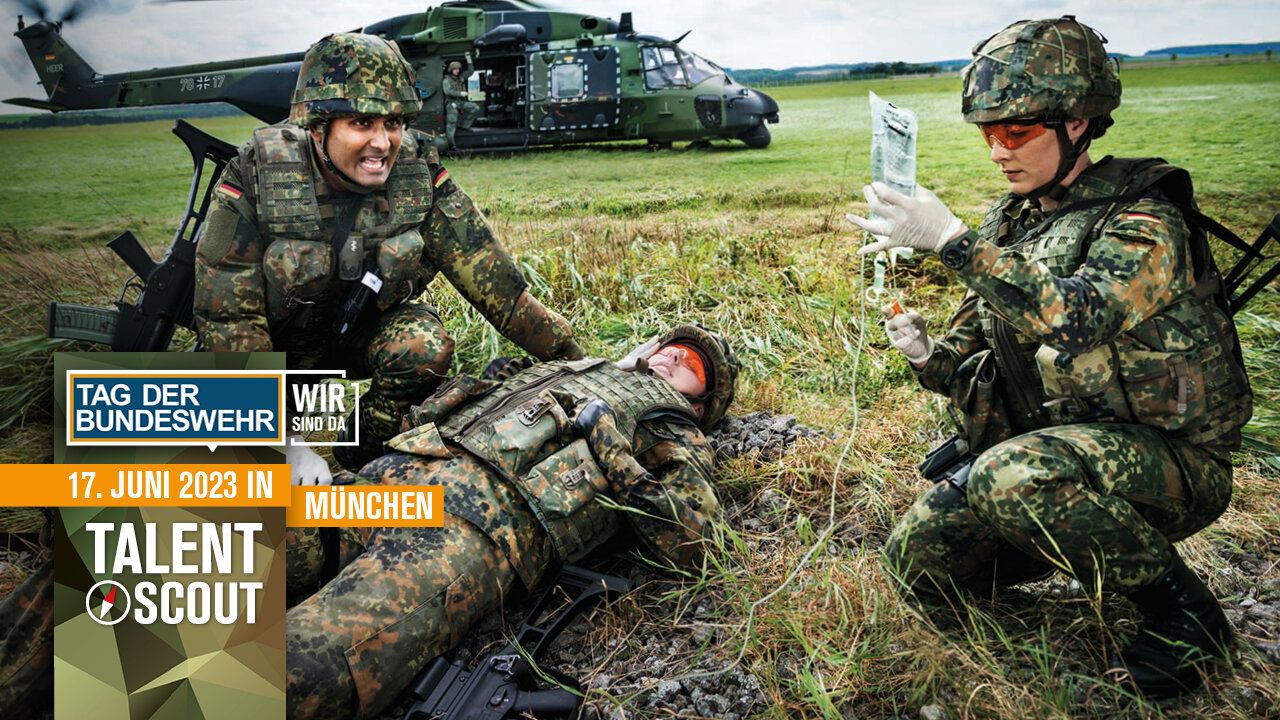 Eine Soldatin und ein Soldat versorgen einen verwundeten Kameraden. Im Hintergrund ist ein Hubschrauber zu sehen.
