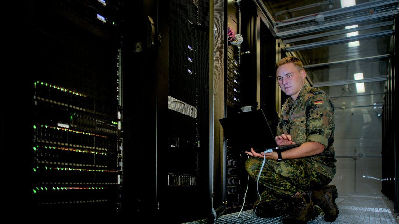 Ein IT Soldat schließt seinen Laptop an einen Server an