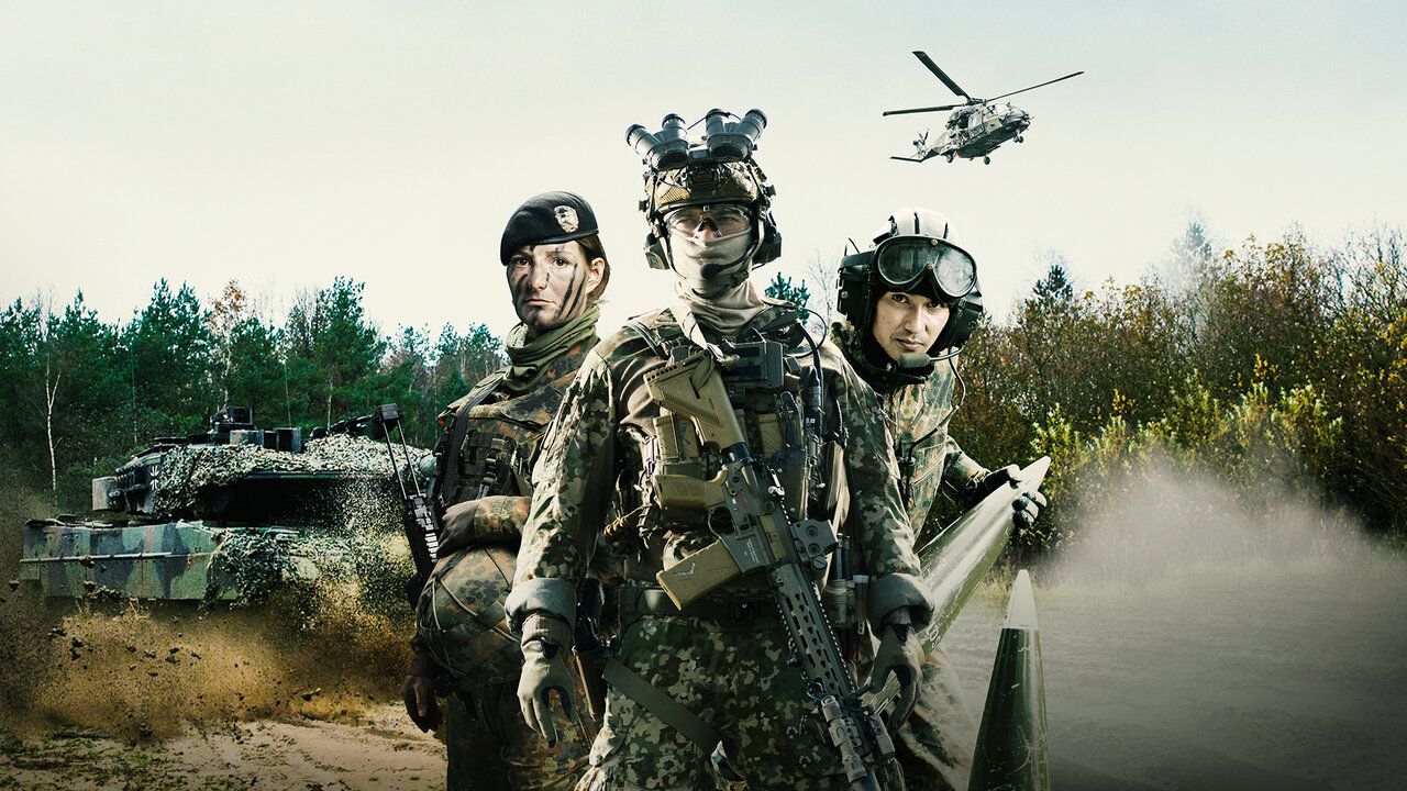 2 Soldaten und eine Soldatin stehen im Gefechtsanzu nebeneinander. Links im Hintergrund fährt ein Panzer der Bundeswehr und am Himmel fliegt ein Hubschrauber der Bundeswehr.