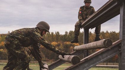Soldaten überwinden unter Aufsicht eines Ausbilders ein Hindernis auf der HiBa