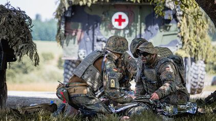 Kameraden der Sanitätstruppe versorgen einen verwundeten Kameraden im Feld