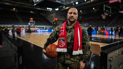 Ein Soldat der Bundeswehr steht mit einem Basketball in einer Arena