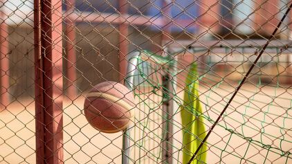 Ein Basketball springt in einer Halle hinter einem aufgestellten Tor in die Luft. 