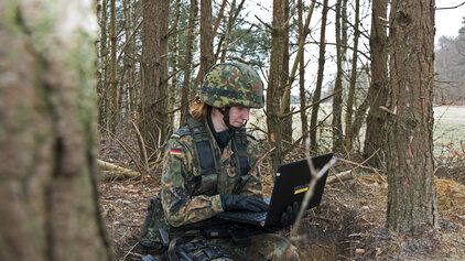 Soldatin mit Laptop im Wald
