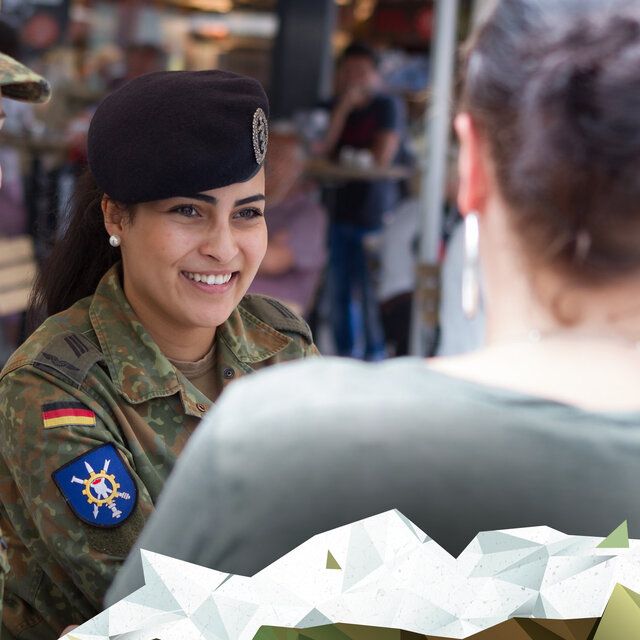 Eine Soldatin der Bundeswehr unterhält sich mit einer zivilen Dame. 