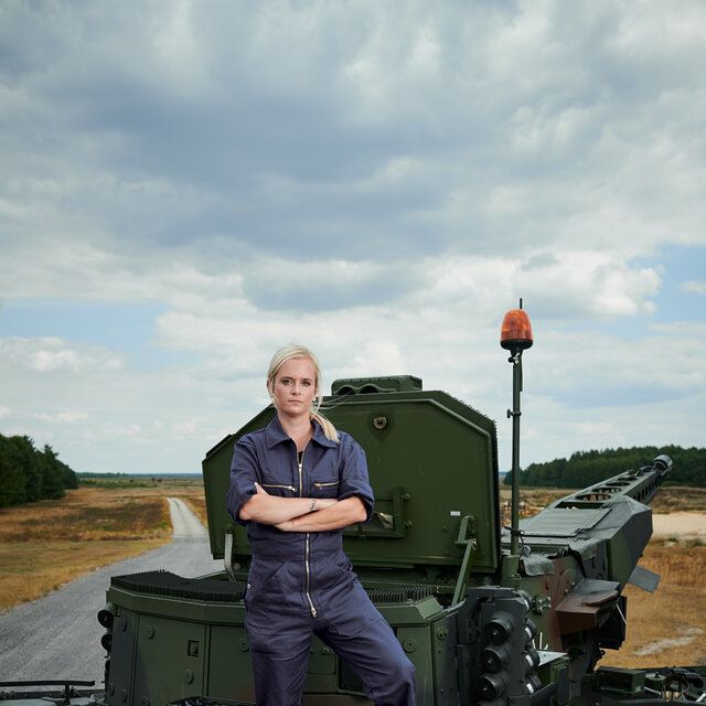 Technikerin steht mit verschrÃ¤nkten Armen auf dem SchÃ¼tzenpanzer Puma auf einem TruppenÃ¼bungsplatz