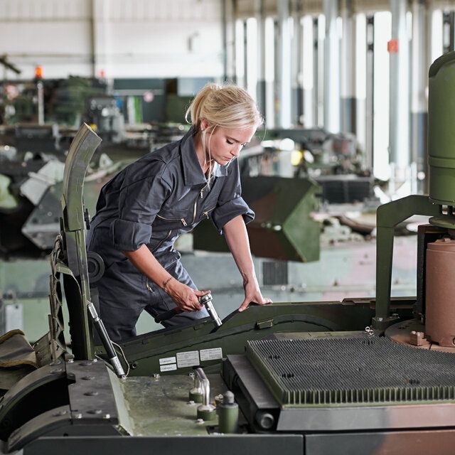 Eine Technikerin fÃ¼hrt Montagearbeiten an einem SchÃ¼tzenpanzer durch.