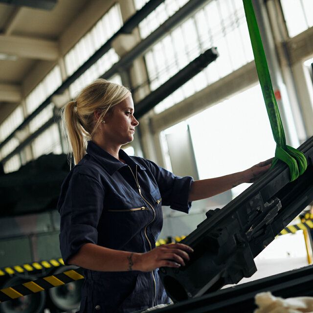 Eine Technikerin arbeitet in einer Halle an Anbauteilen des SchÃ¼tzenpanzers.
