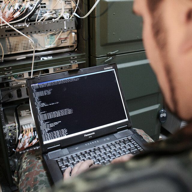 Ein IT-Spezialist der Bundeswehr liest mit seinem Laptop Daten vom Server aus.