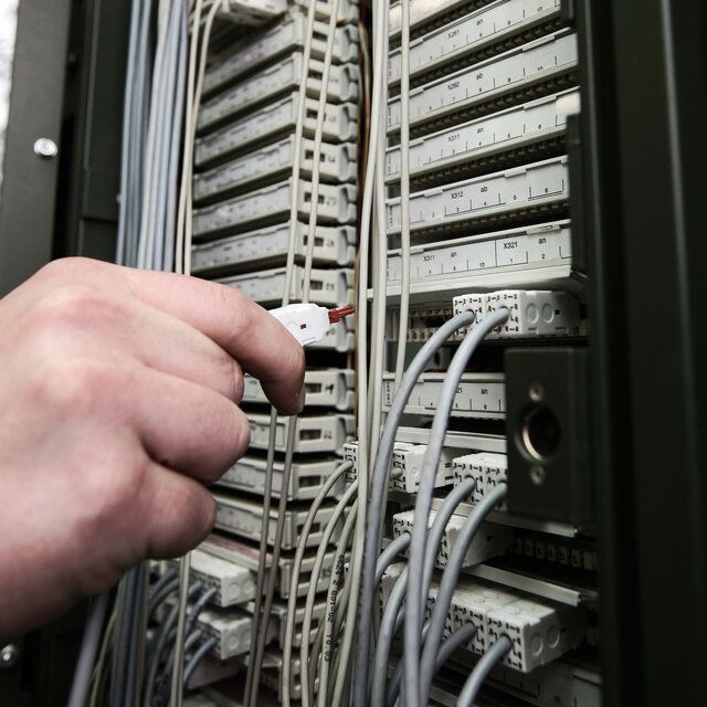 Ein Kabel wird am Netzwerkschrank angebracht. 