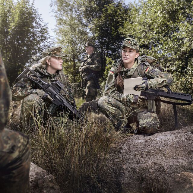 Soldat_innen besprechen im Rahmen einer Ãœbung die Lage im Wald. 