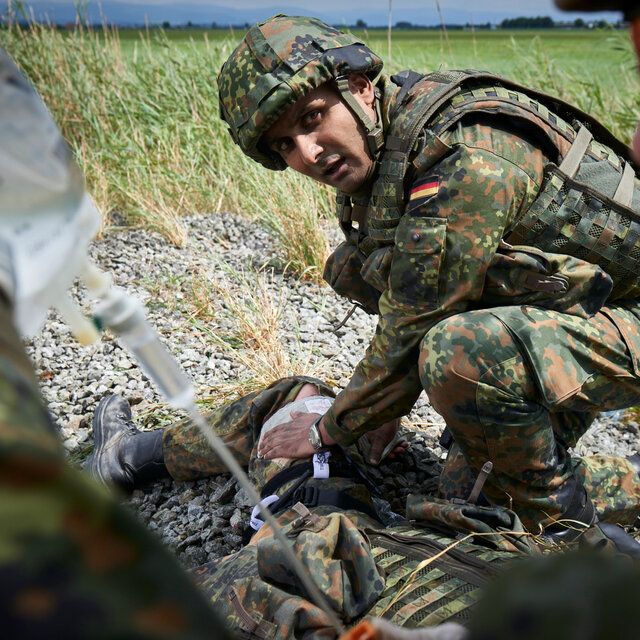 Ein Soldat im Felde leistet einem verletzten Kameraden erste Hilfe. 